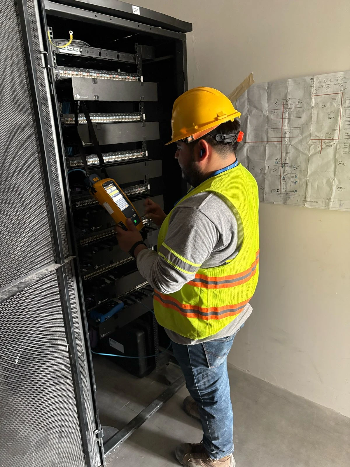 Técnico certificando puntos de red en un rack de telecomunicaciones